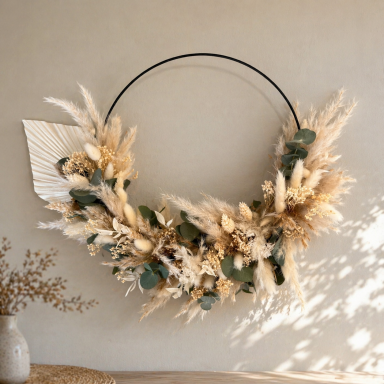 Kranz aus getrockneten Blumen und Gräsern, dekorativ an einer Wand hängend.
