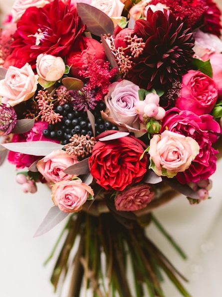 Bunter Blumenstrauß mit roten, rosa und lila Blumen sowie grünen Blättern.