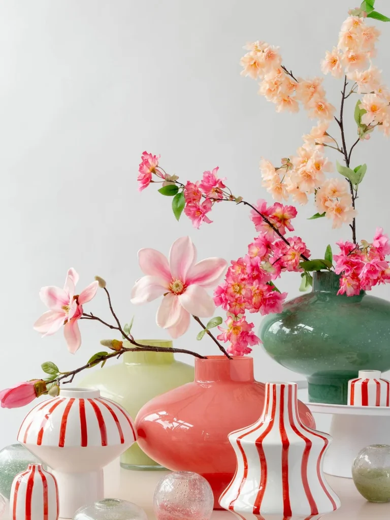 Bunte Vasen mit blühenden Zweigen und Dekor in Pastelltönen.