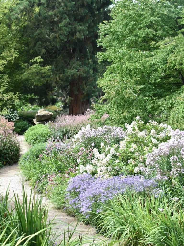 Bunte Blumen und grünes Laub in einem angelegten Garten mit geschwungenen Wegen.